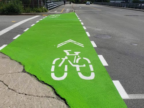 Marquage de piste cyclable verte avec symbole vélo sur chaussée.